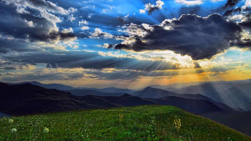 mountain with sunlight shining behind clouds