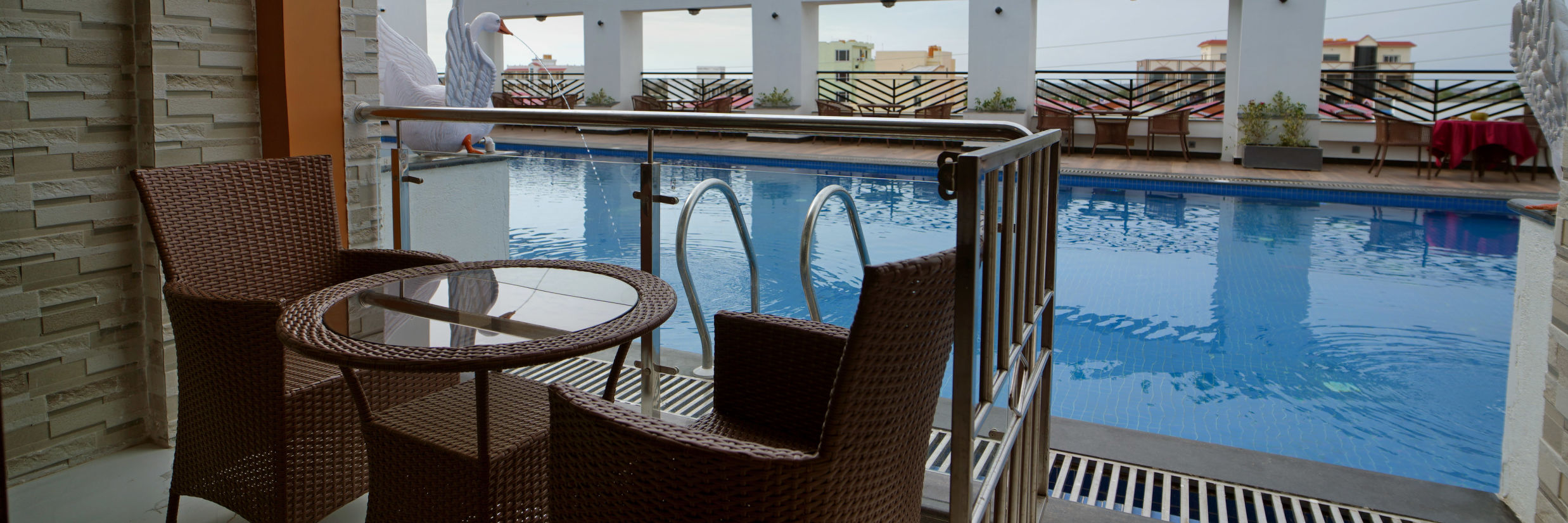 Seats in a balcony with a small table with views of the swimming pool inside one of the rooms - Shanti Seaview Resort & Spa