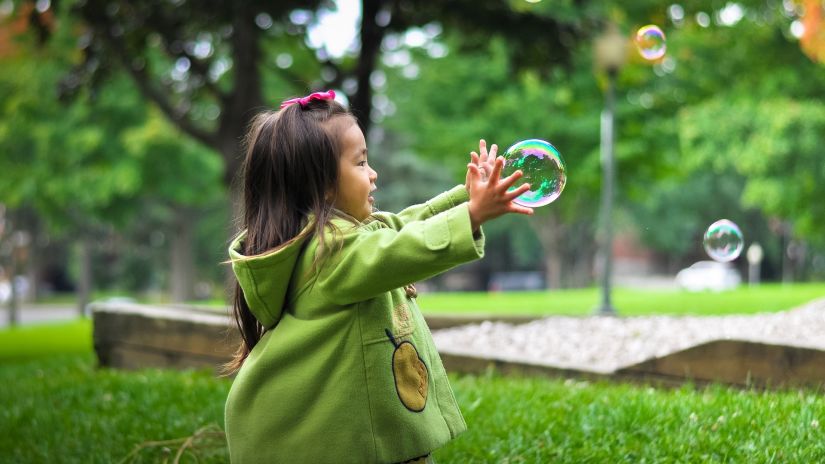 a small girl playing with a bubble