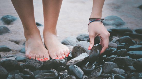 a woman picking up pebbles from a sea beach