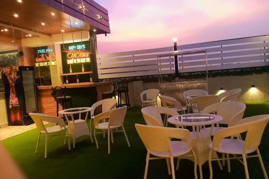 alt-text an image of kapil dev eleven resto displaying a set of lounge chairs placed in open air - Click Hotel Capital House, Patna