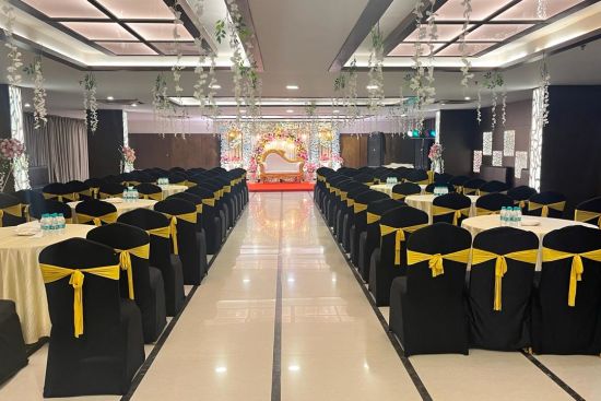 alt-text chairs around the tables facing towards the stage adorned with flowers and lights