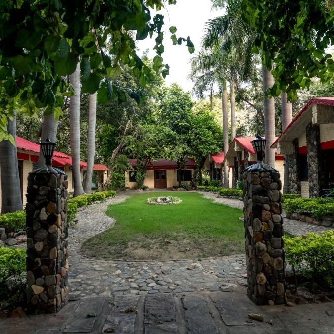 Entrance to the resort with plants next to a stone pillar - Leopard Lair Ananta Express, Bera