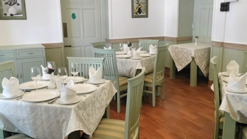 Brij Villa Dalhousie - interior view of the restaurant featuring green colour furniture and wooden flooring