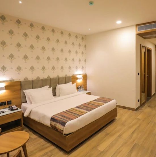 executive room at Comfort Resort, Morbi displaying elegant golden prints on white wall with a bed placed in it