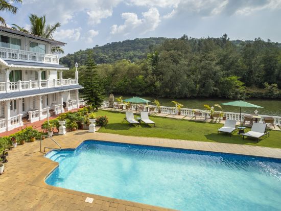 The facade of the hotel alongside the pool - Stone Wood Riverfront Resort, Siolim