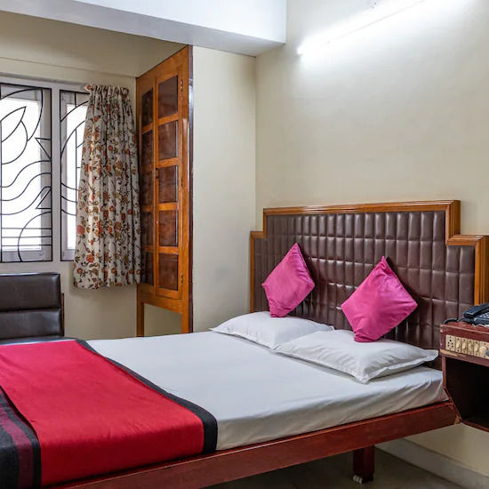 alt-text Side view of Double room with plush bed, side table and large window - Hotel Ram International,  Pondicherry