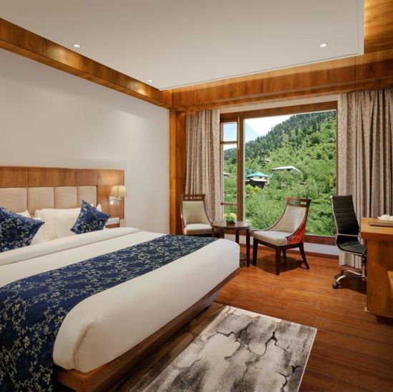 alt-text Room with a commodious bed and wooden furnishings overlooking lush greenery