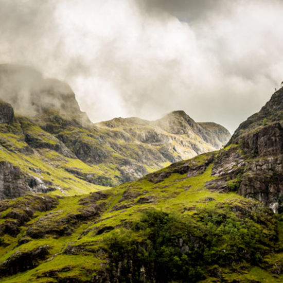 a valley in between two mountains with dark clouds in the background 