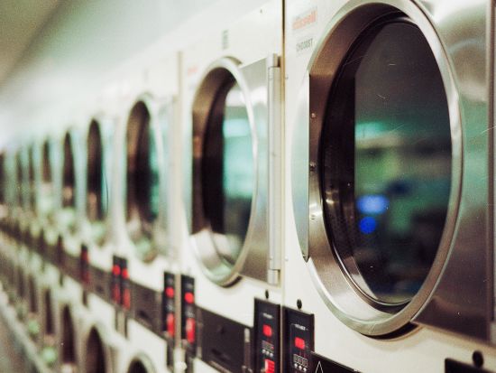 Many washing machines stacked next to each other inside a room