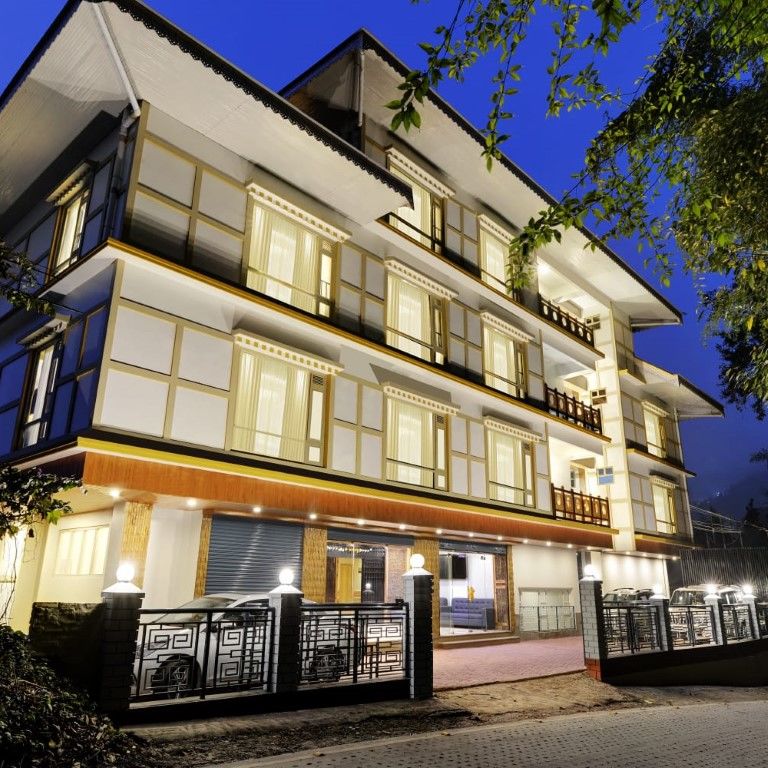 A low high angle of facade of a well-lit 3-storey building at night | Sumi Yash Shree Hotels & Resorts