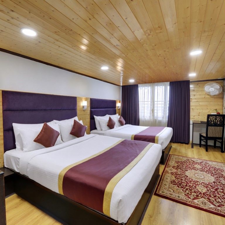 Premium Triple bedroom with two large beds facing a television and side lamps and purple curtains - Sumitel Boutique Resort, Darjeeling