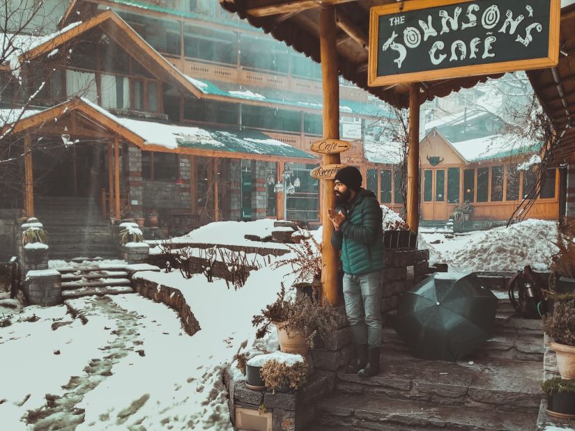 A man outside a cafe taking in the snowy scene