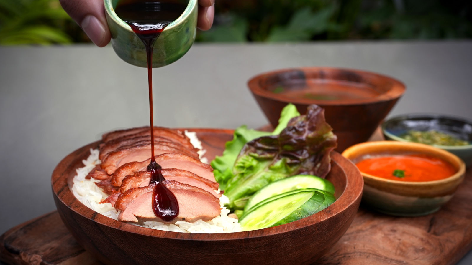 sauce being poured on Hainanse Duck with dip on the side at Village 36