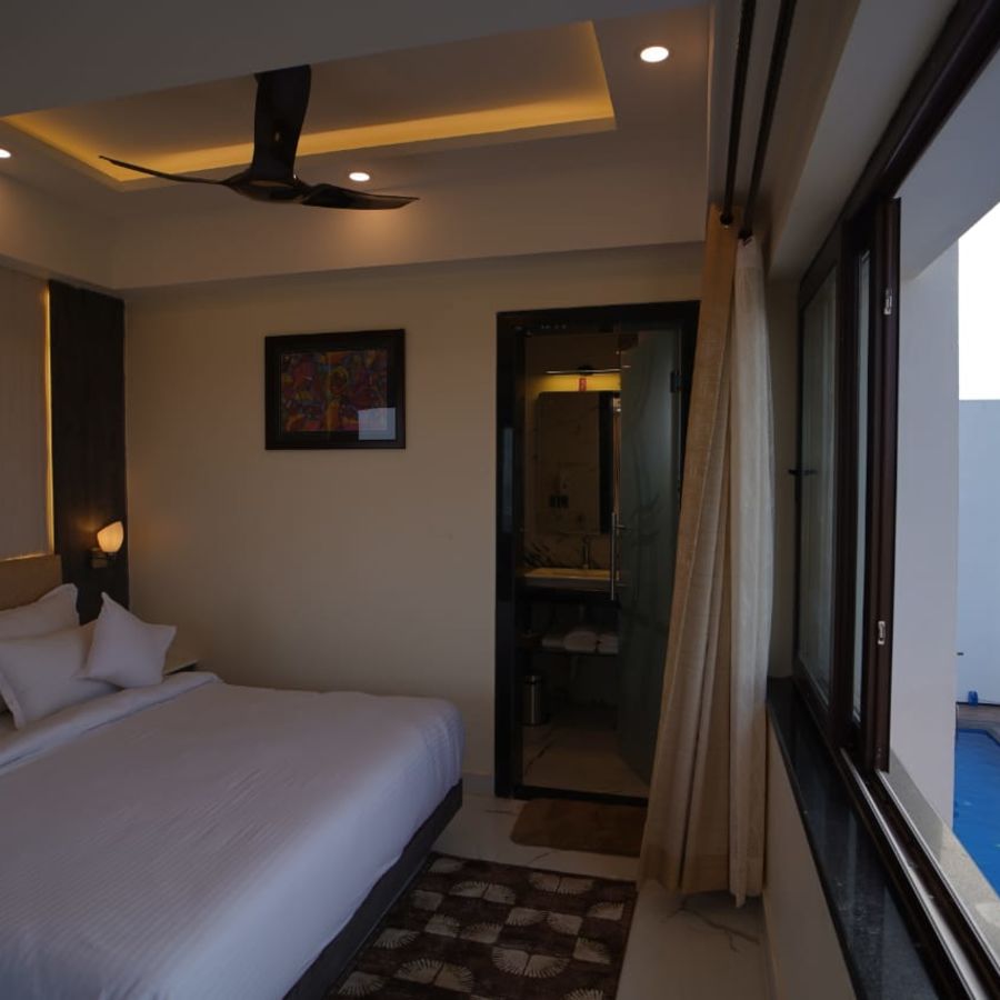 a double bed with a massive glass window opposite the bed in one of the rooms - Shanti Seaview Resort & Spa