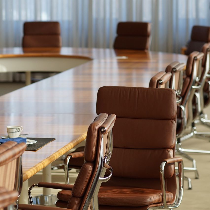 A meeting room featuring a u shaped table and brown leather chairs