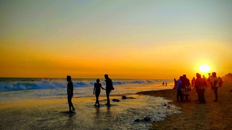 People standing by a beach during sunset