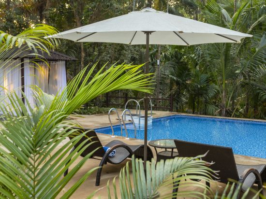 A swimming pool with beach loungers and a parasol on the side - Stone Wood Nature Resort, Gokarna