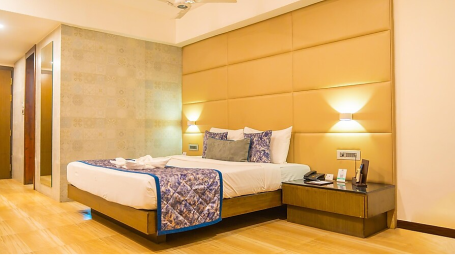 Premium room view with a large bed in a well lit room with a side drawer - Yashshree Milestone, Siliguri