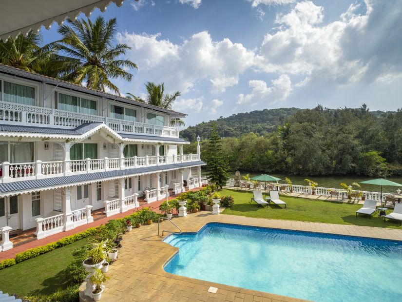 The facade of the hotel alongside the pool - Stone Wood Riverfront Resort, Siolim