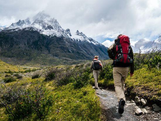 A man and a woman trekking on a mountain trail