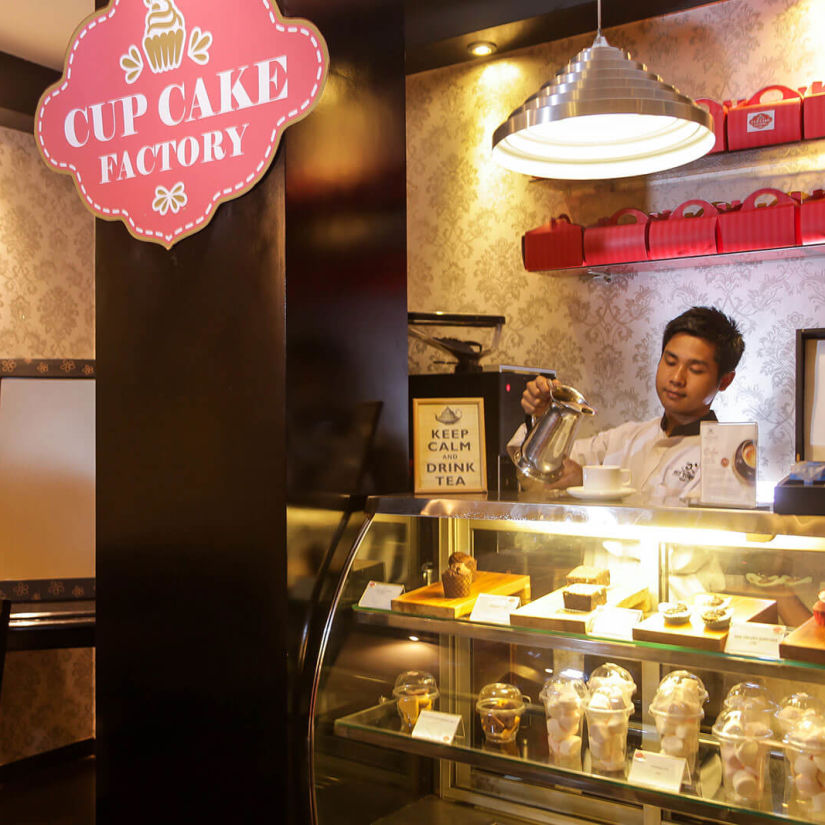 a man standing behind a bakery counter