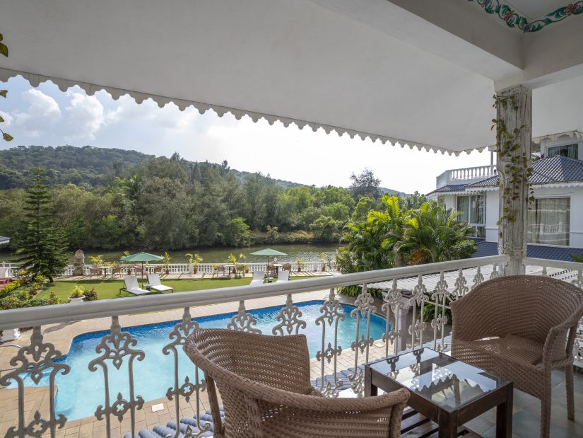 The Maharaj Balcony overlooks the pool and lush green hills - Stone Wood Riverfront Resort, Siolim