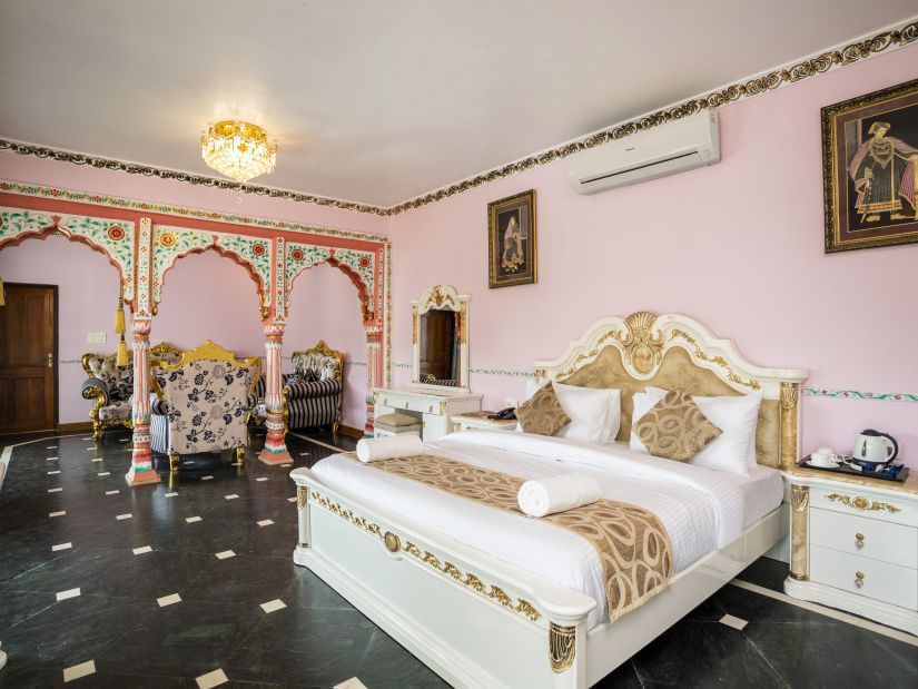 The pink walls and white bedding at the Maharaja Suite Bedroom - Stone Wood Riverfront Resort, Siolim