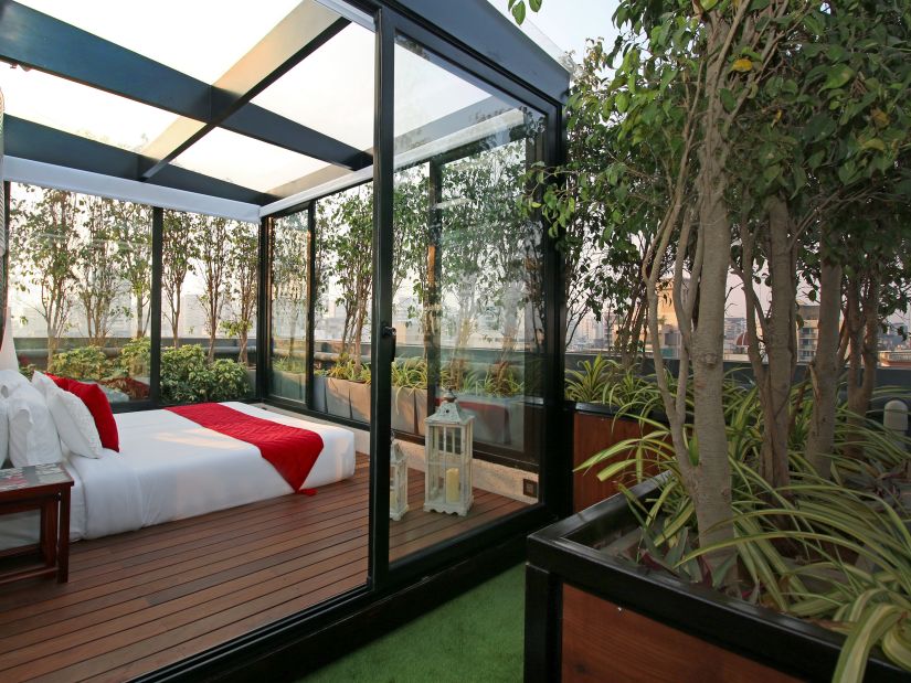 bedroom with glass windows next to potted plants in the terrace - Theory9 - Premium service apartments, bandra