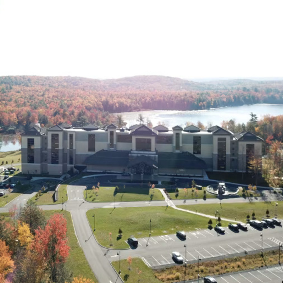 Picturesque aerial view of YO1 Resort under on a sunny day featuring trees that have turned orange and brown due to fall and a parking lot