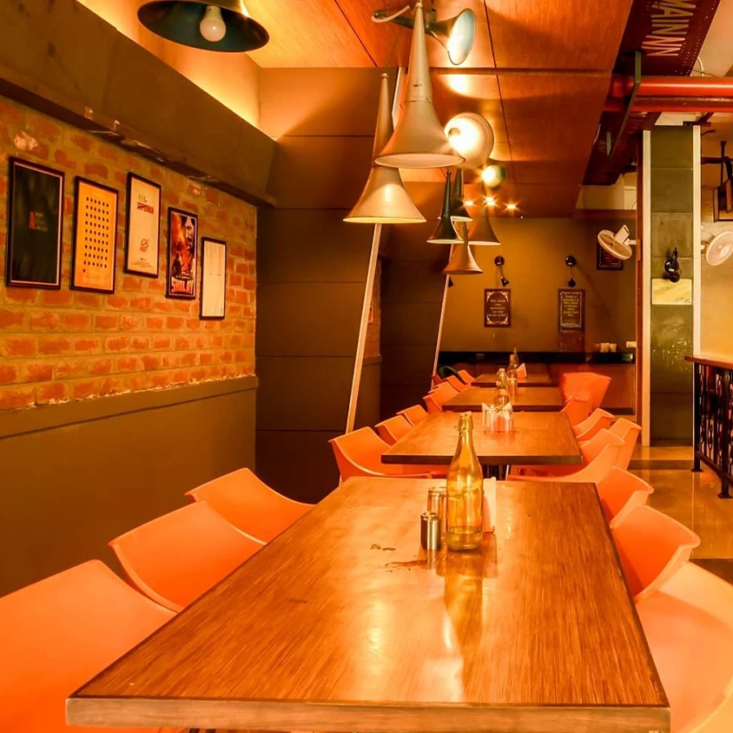 A contemporary hotel dining space with long wooden tables, modern chairs, and eclectic wall art creating a casual yet stylish ambiance.