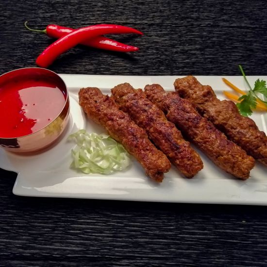 alt-text The seekh kebab with sauce and garnished with veggies.