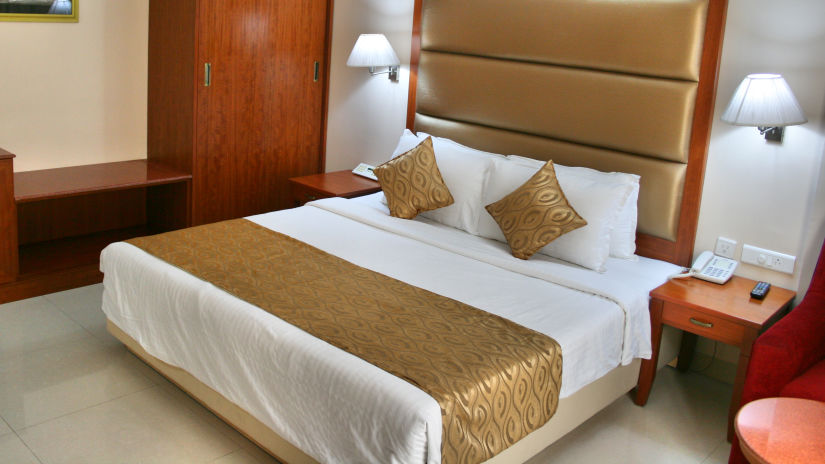 a double bed, wardrobe, bedside tables and lamps in one of the Superior Rooms at Raj Park Hotel, Tirupati