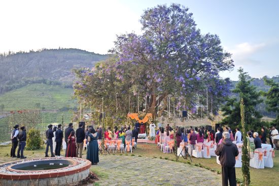 alt-text Panoramic view of an outdoor wedding ceremony with guests seated around a central lawn under trees in Coonoor.