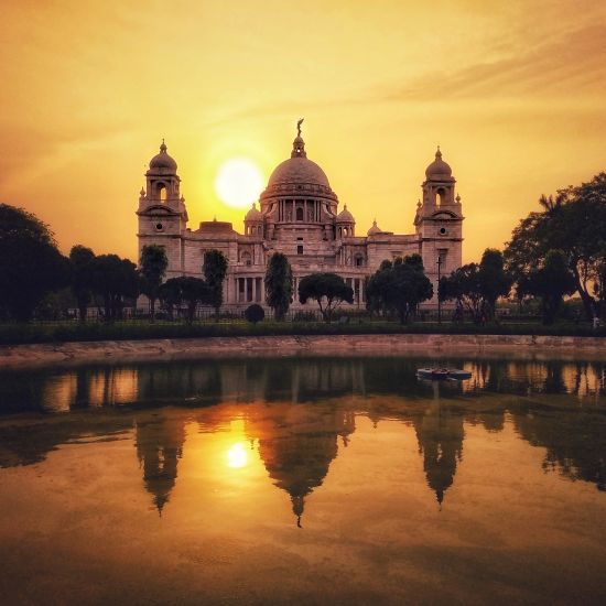 the facade of Victoria Memorial during evening time with the sun setting in the background