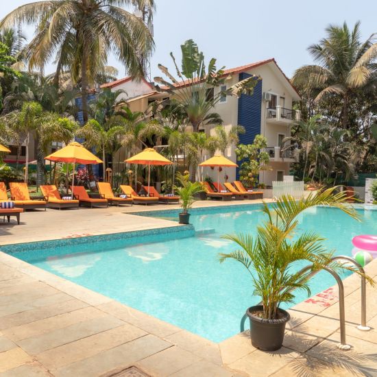 Swimming Pool at Kyriad Prestige Calangute, Goa surrounded by beach chairs