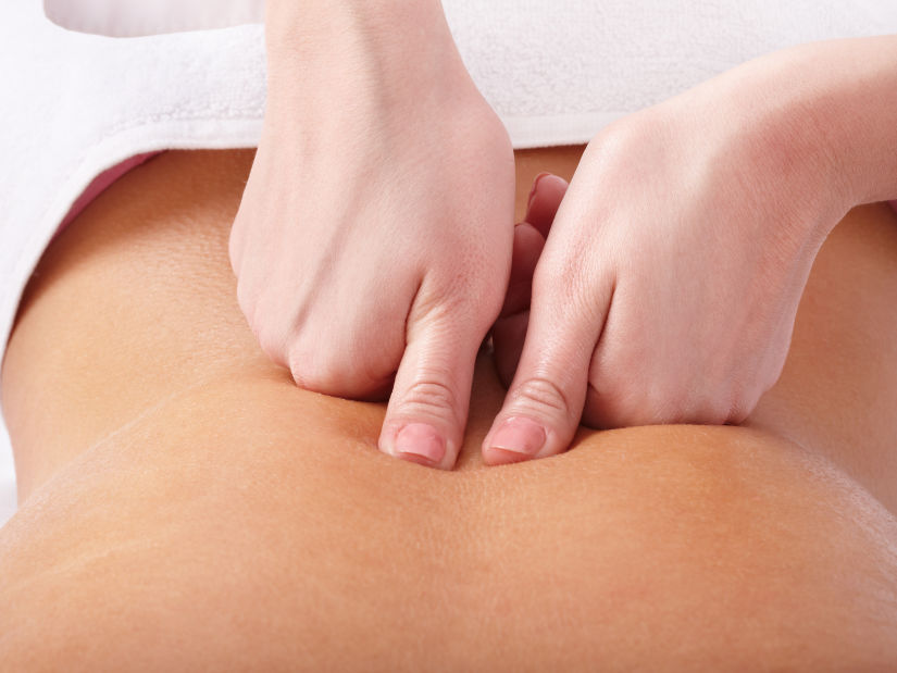 a masseuse using kneading technique while massaging the back of a customer