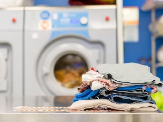 Freshly laundered clothes neatly placed on a table with laundry machines in the background