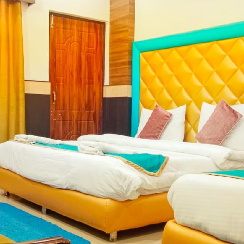 Triple Bed deluxe room with blue and white bed covers at Hotel Panchvati Inn, Joshimath