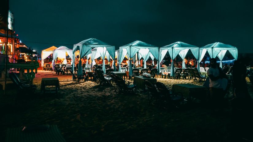 a beach shoreline dotted with well-lit stalls