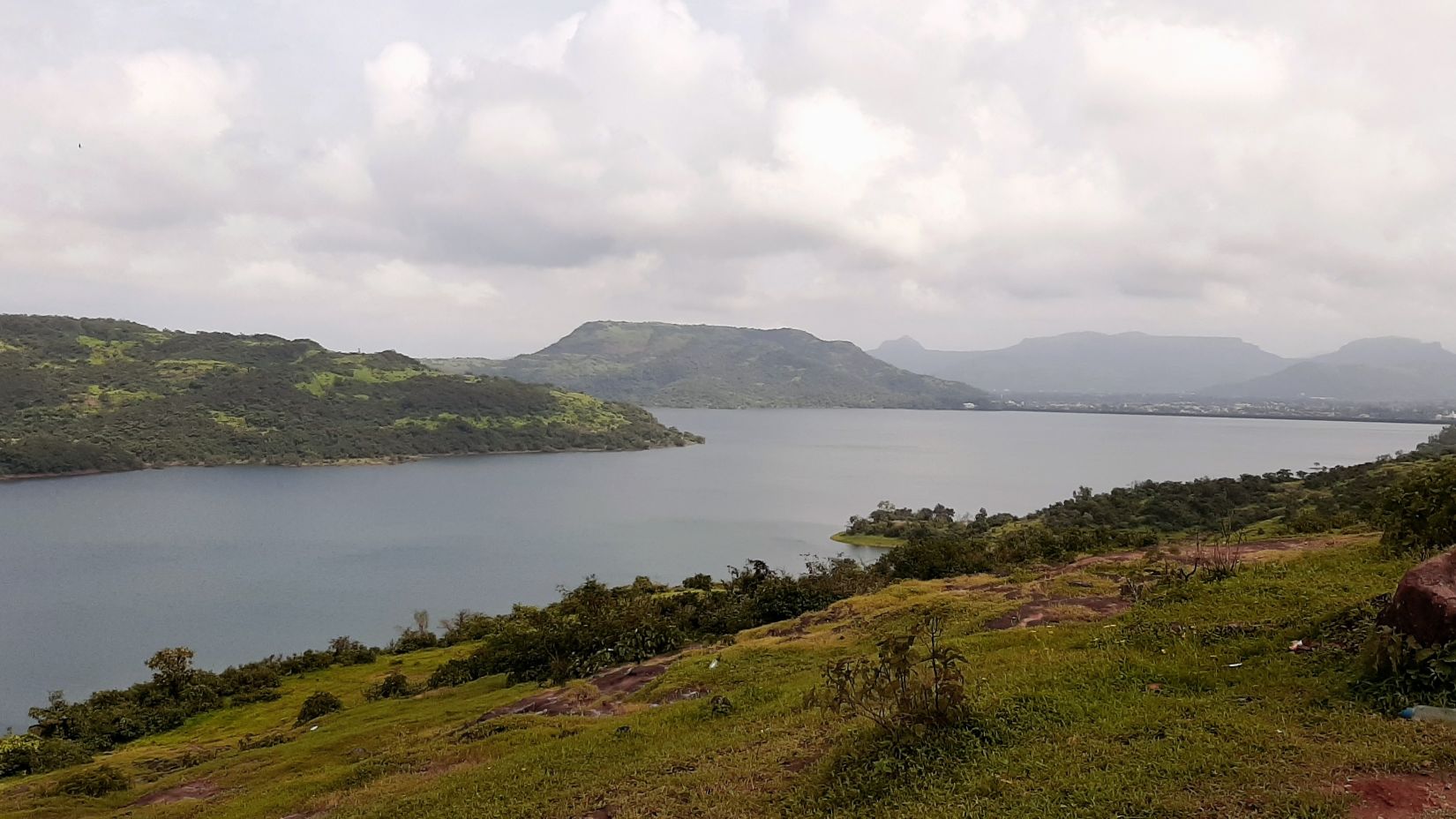 a view of a lake in lonalava from afar with hills in the background