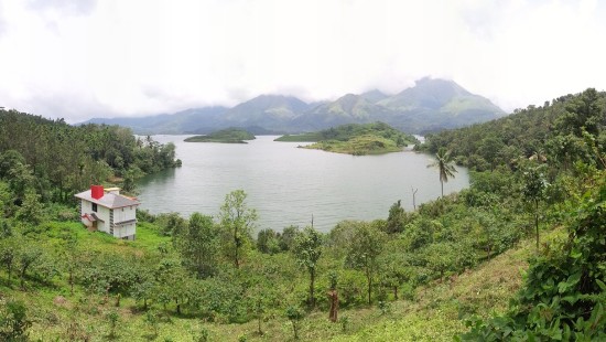 a house beside a lake amidst green hills