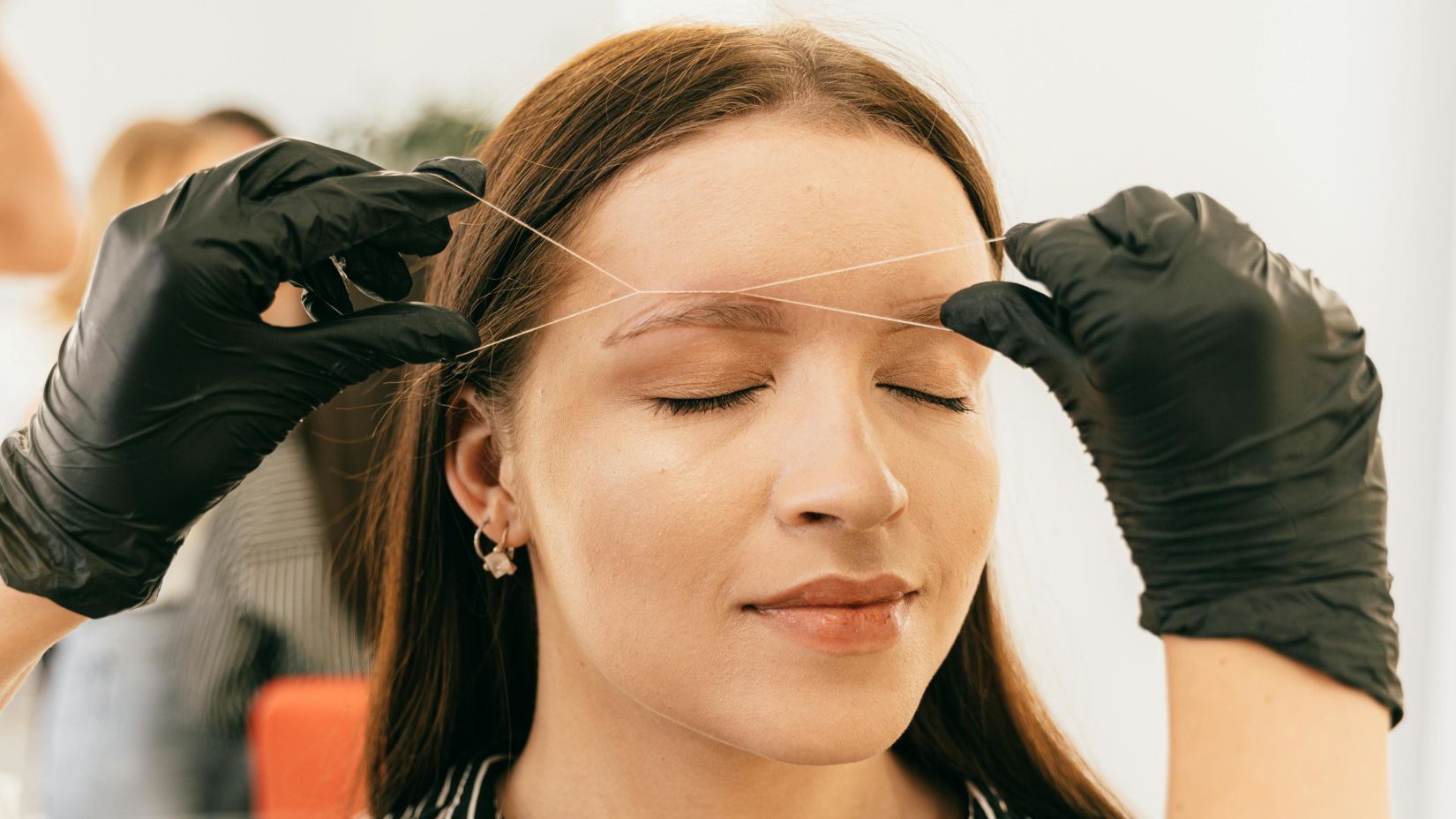 a woman getting her threading done in a salon by a professional