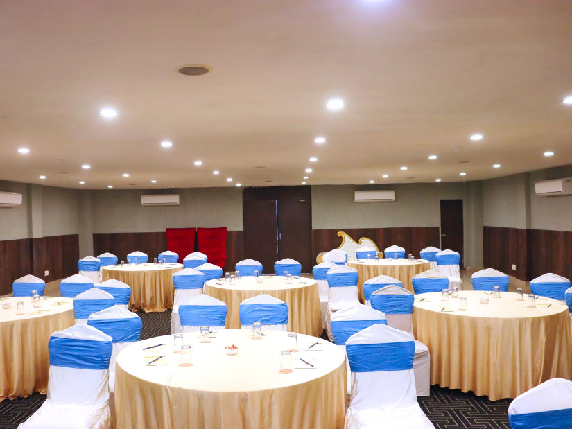 The banquet hall is set up with round seating tables at Clarks Collection, Bhavnagar