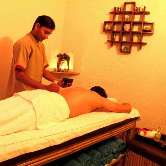 a masseur applying essential oils on a customer for spa