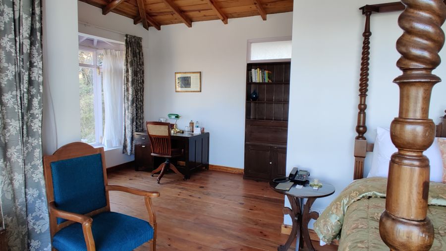 Side view of  Superior Room with chair on the side on and wooden bed frames at Te Aroha by Shervani Mukteshwar