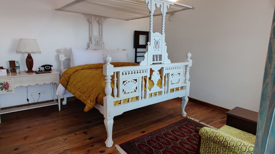 Premium room with intricately designed bed and a table on the side of the bed with a lamp at Bed with side canopy and a lamp on the side of the bed at 3 bhk cottage at Te Aroha by Shervani Mukteshwar