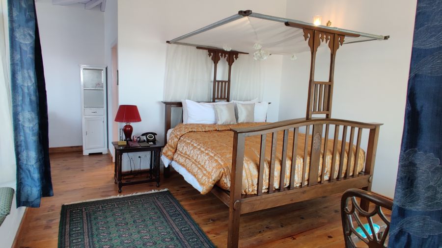 Premium room with wooden bed and rug by the side of the bed at Bed with side canopy and a lamp on the side of the bed at 3 bhk cottage at Te Aroha by Shervani Mukteshwar