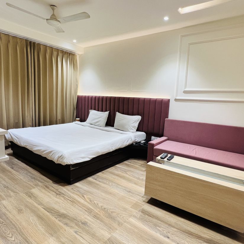 Premium Bedroom with white beddings, mahognagy headrest and mathcing sofa - Morya Regency, Bhopal