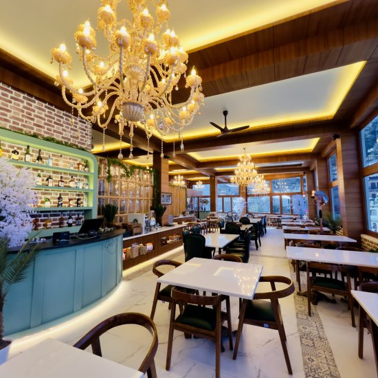 alt-text chairs placed around a dining table with chandelier hanging from the ceiling at Alenprose Restaurant in The Tattva Boutique Resort, Joshimath